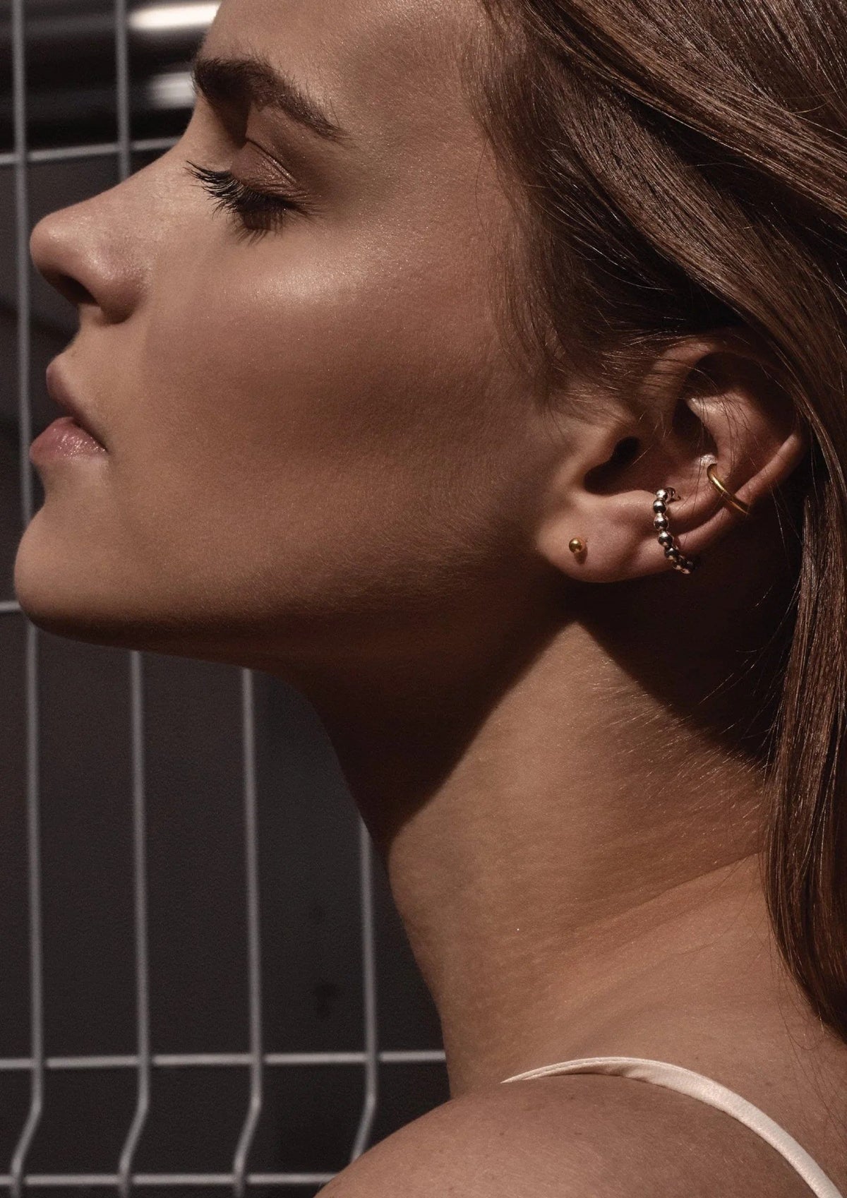 5. Women's gold pin-up earrings worn by model with additional gold jewelry, shown in profile view