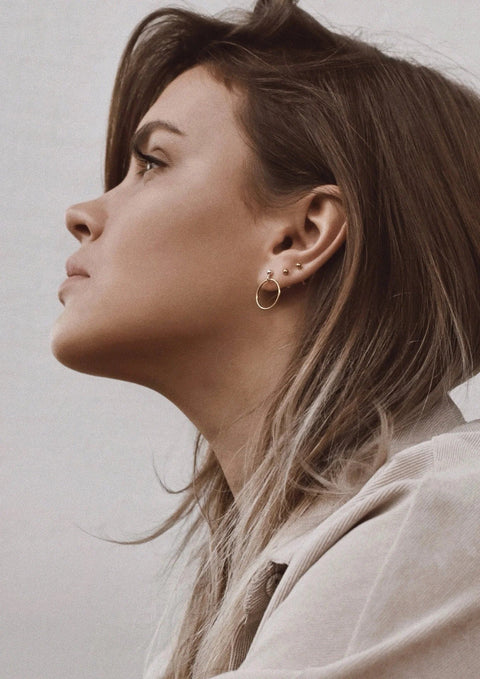 3. Women's gold pin-up earrings worn by model with layered earrings, shown in profile view