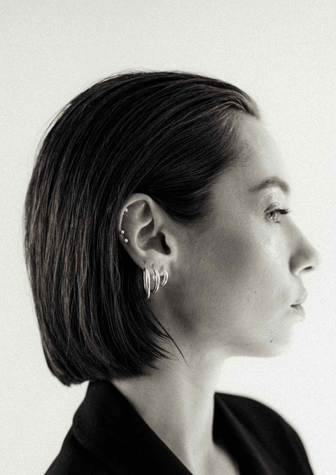 4. Woman with short hair wearing NO MORE Pin Up Earrings in sterling silver, paired with multiple hoop earrings