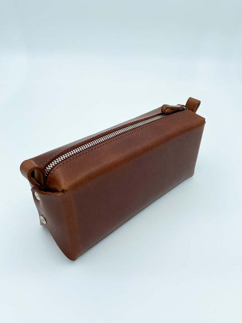 4. Brown leather makeup bag by Stella Soomlais with silver zipper on white background, emphasizing clean lines