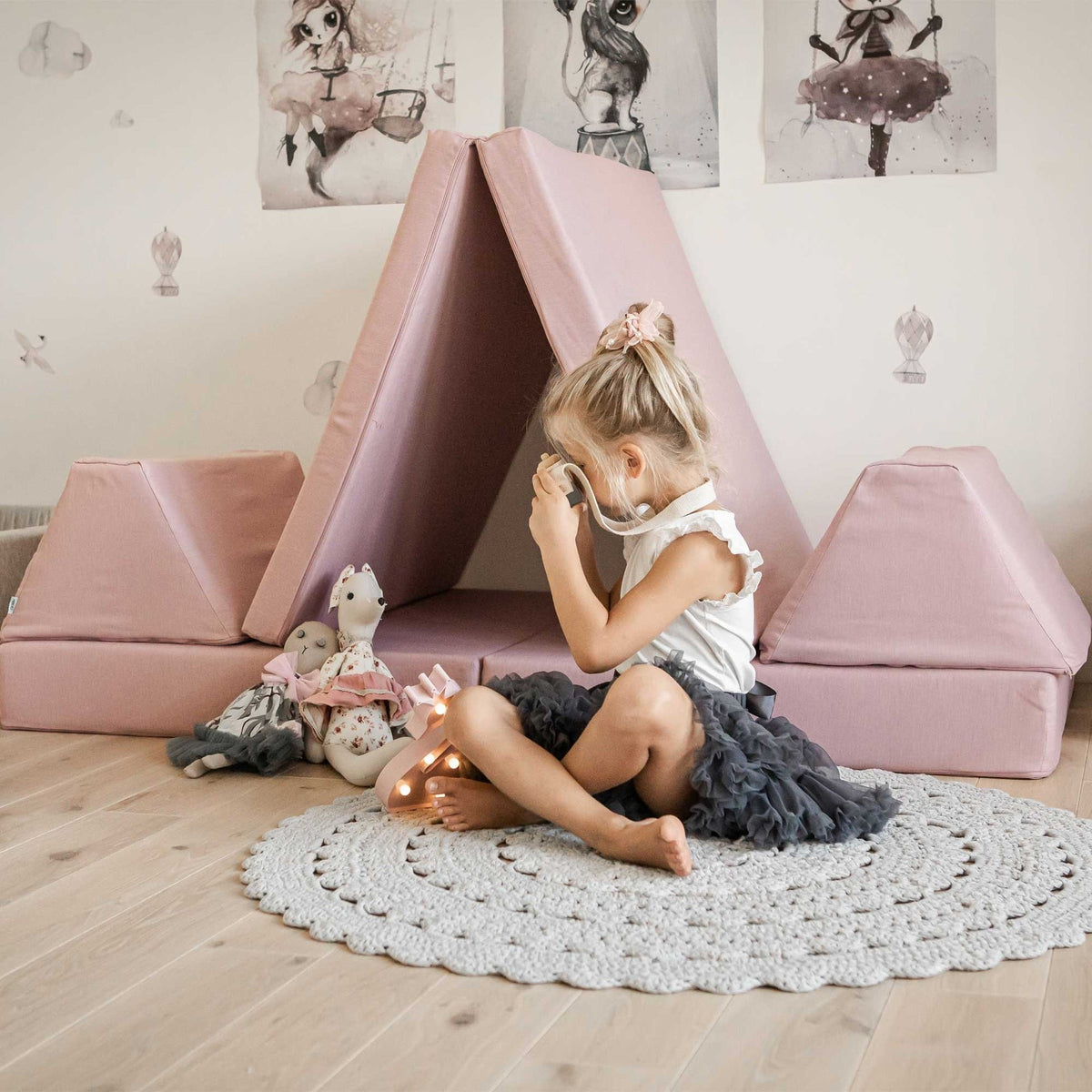 1. Girl playing with pink play mattress set arranged as a tent in a decorated room