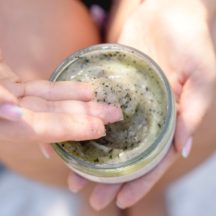 2. Close-up of woman applying Vegan Fox Peppermint Body Scrub, highlighting texture and natural ingredients