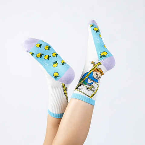 1. Woman's legs wearing multicolor Pippi Longstocking socks with cartoon design, featuring blue, purple, and yellow accents, against a white background