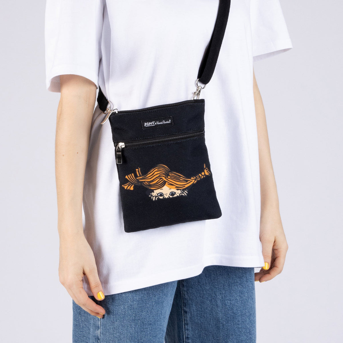 1. Women's Pippi Passport Bag in black by Moomin, worn crossbody with casual outfit