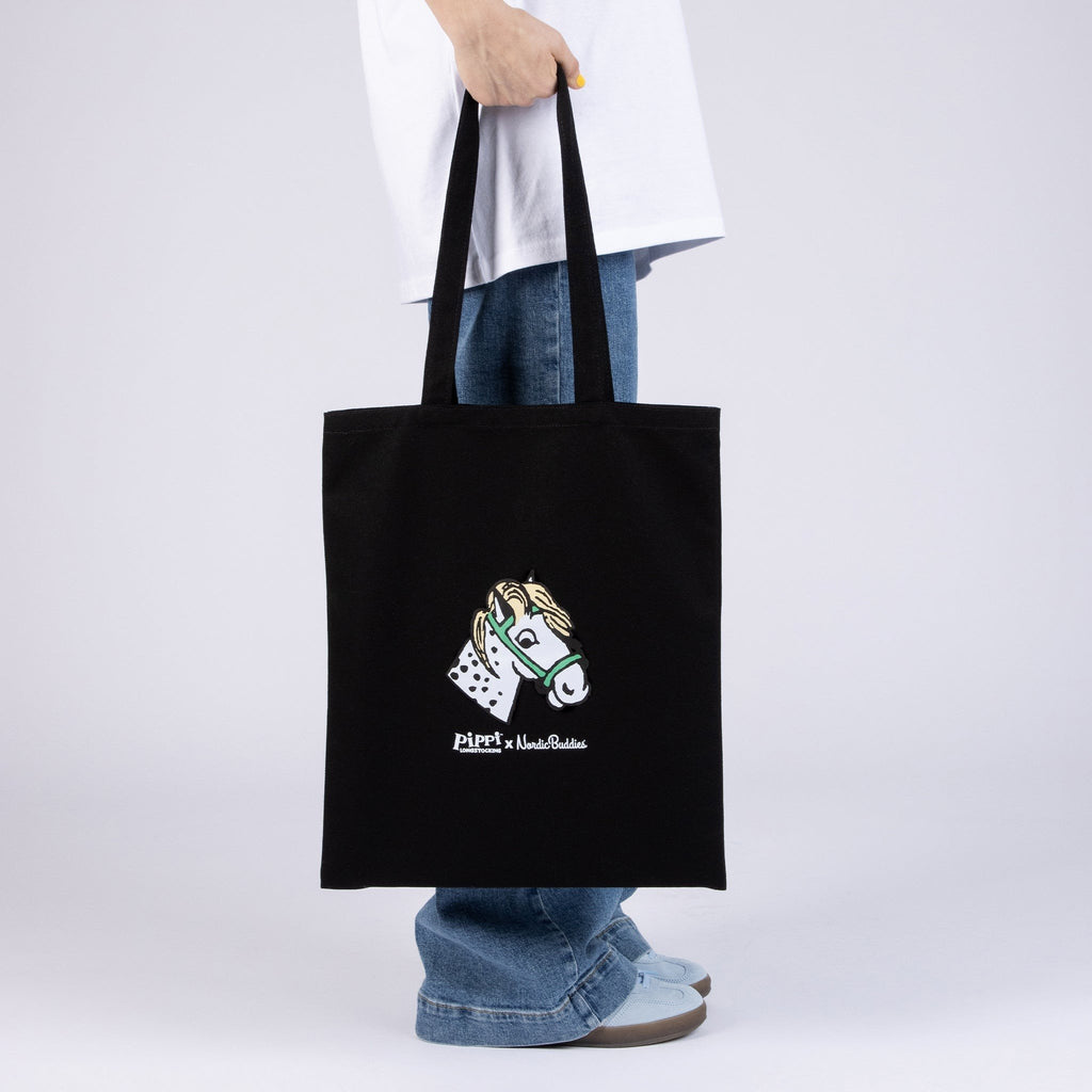 3. Black tote bag with horse head design, held by model in casual outfit