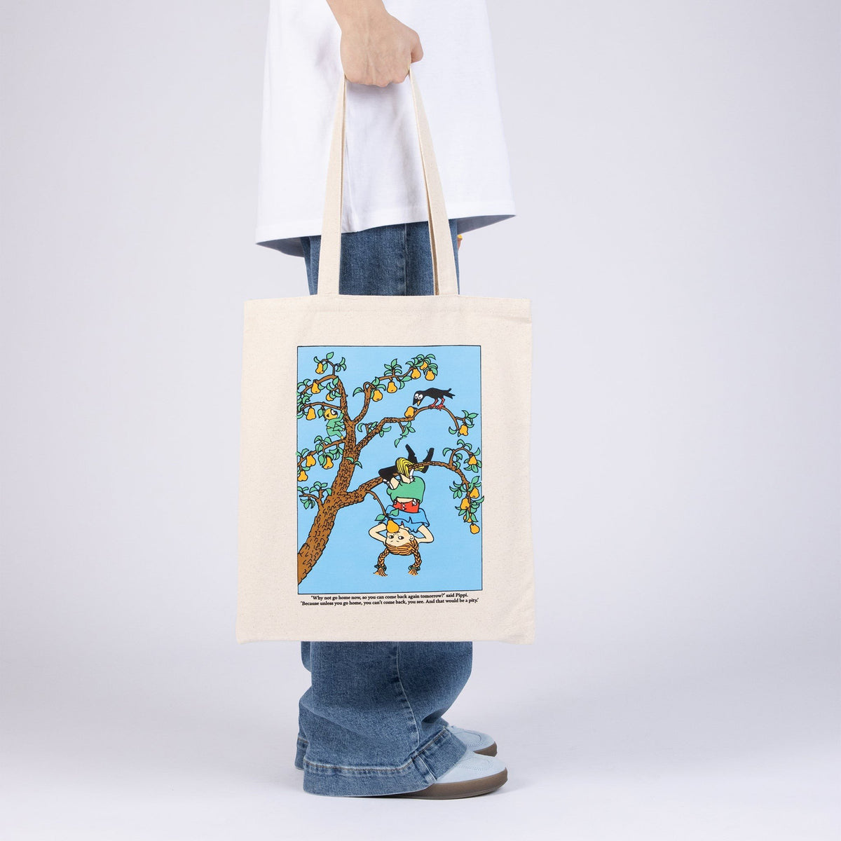 2. Pippi Tote Bag - Upside Down by Moomin, held by a person, featuring colorful Pippi Longstocking tree scene in natural white heavy cotton