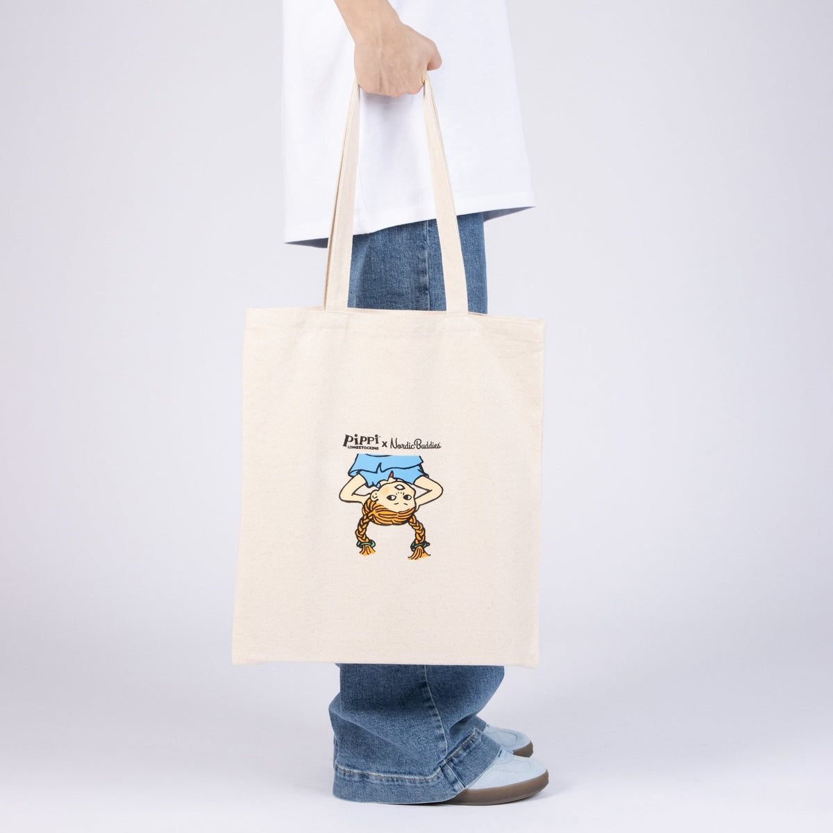 1. Pippi Tote Bag - Upside Down by Moomin, held by a person, showcasing Pippi Longstocking design in natural white heavy cotton