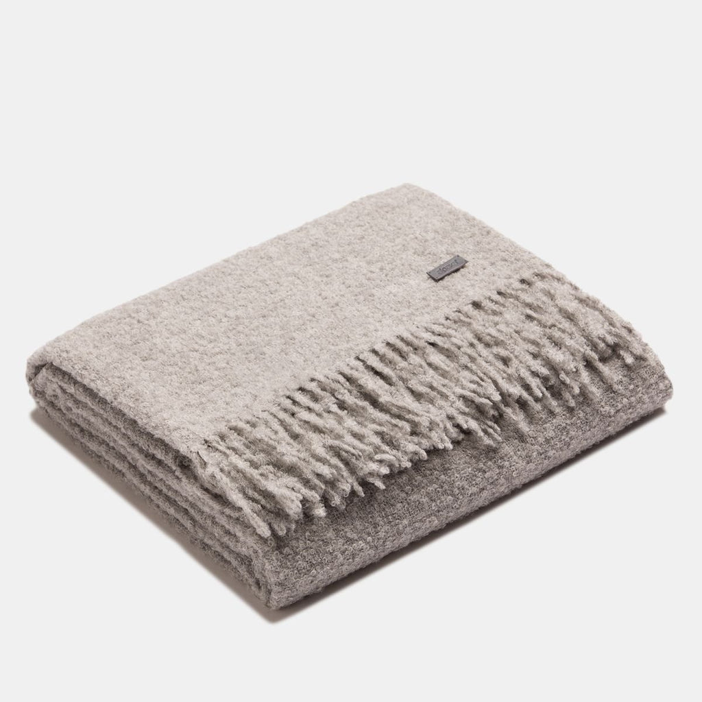 2. Folded grey superfine alpaca wool boucle throw with fringe detailing, showcasing soft texture and elegant design