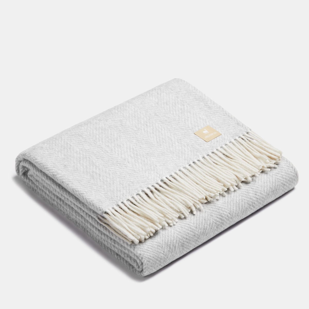 12. Folded light gray Alpaka wool throw with fishbone pattern and fringe in studio