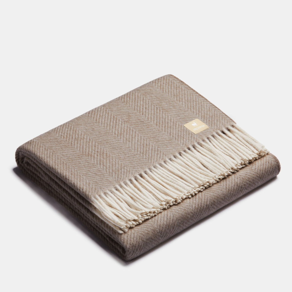 4. Folded beige Alpaka wool throw with fishbone pattern and fringe in studio
