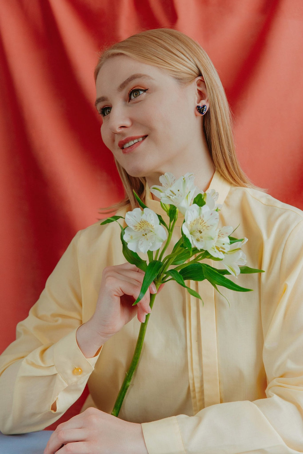 2. Woman holding flowers while wearing Rozenthal blue porcelain heart earrings with gold dots, lifestyle image