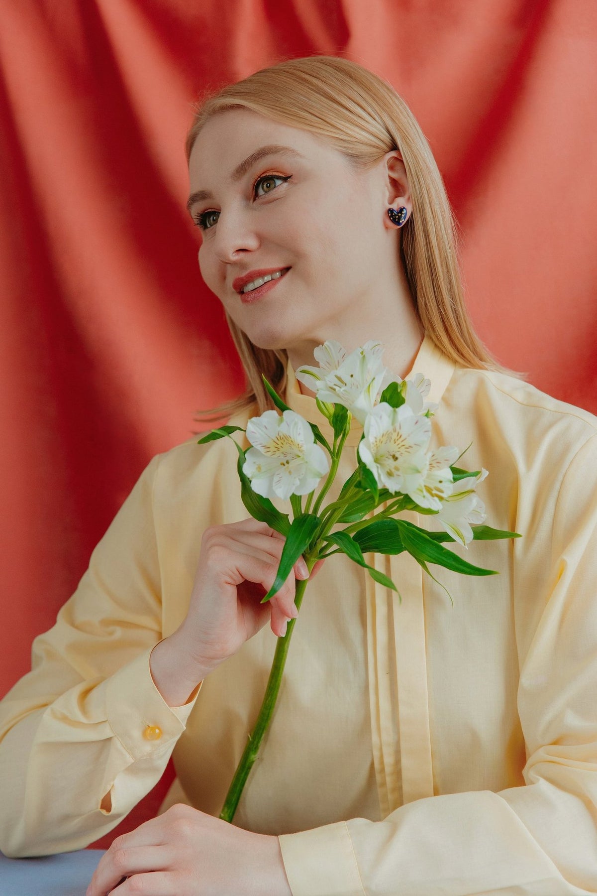 2. Woman holding flowers while wearing Rozenthal blue porcelain heart earrings with gold dots, lifestyle image