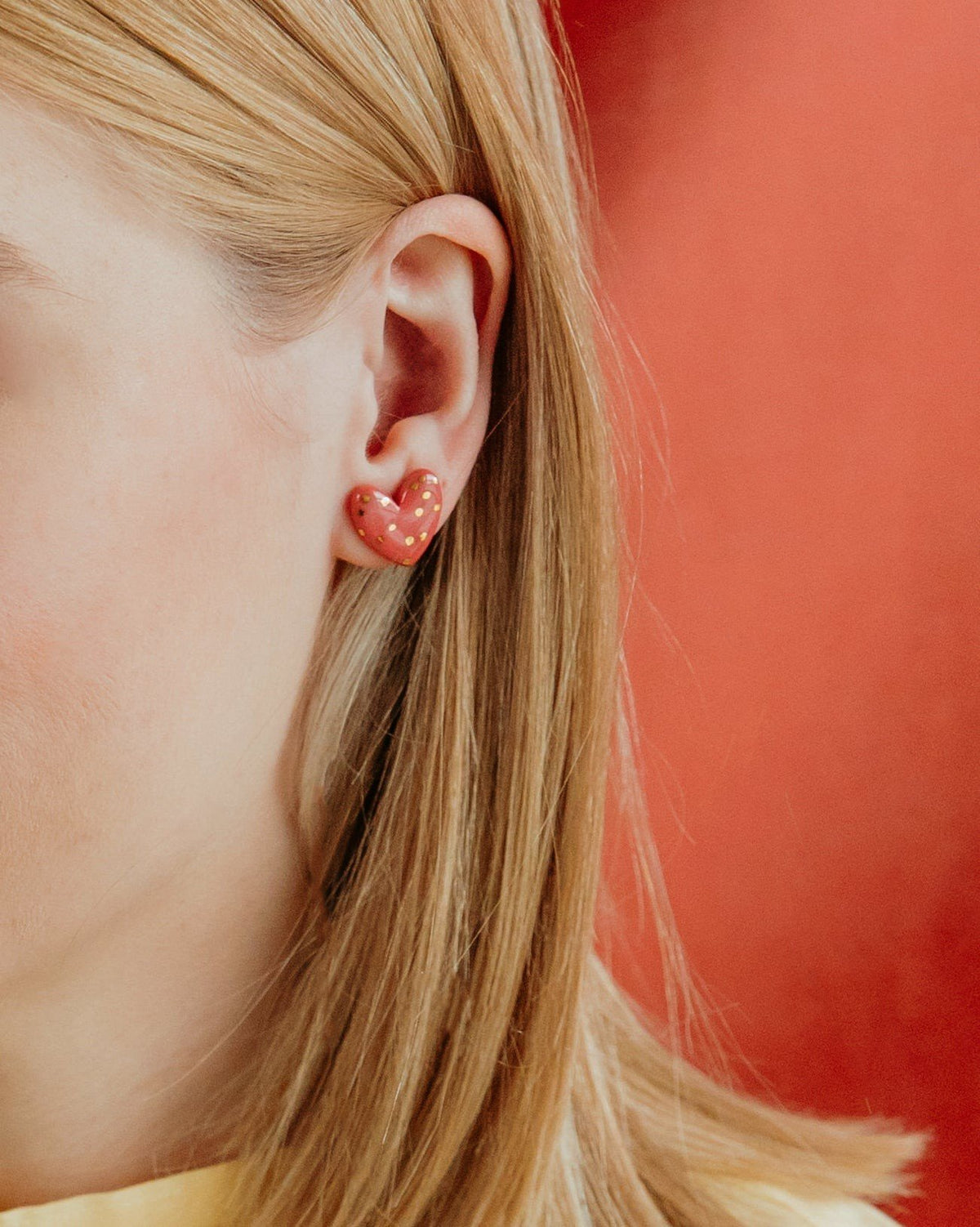 2. Close-up of Rozenthal pink dotted porcelain heart stud earring with 24k gold accents worn by a woman