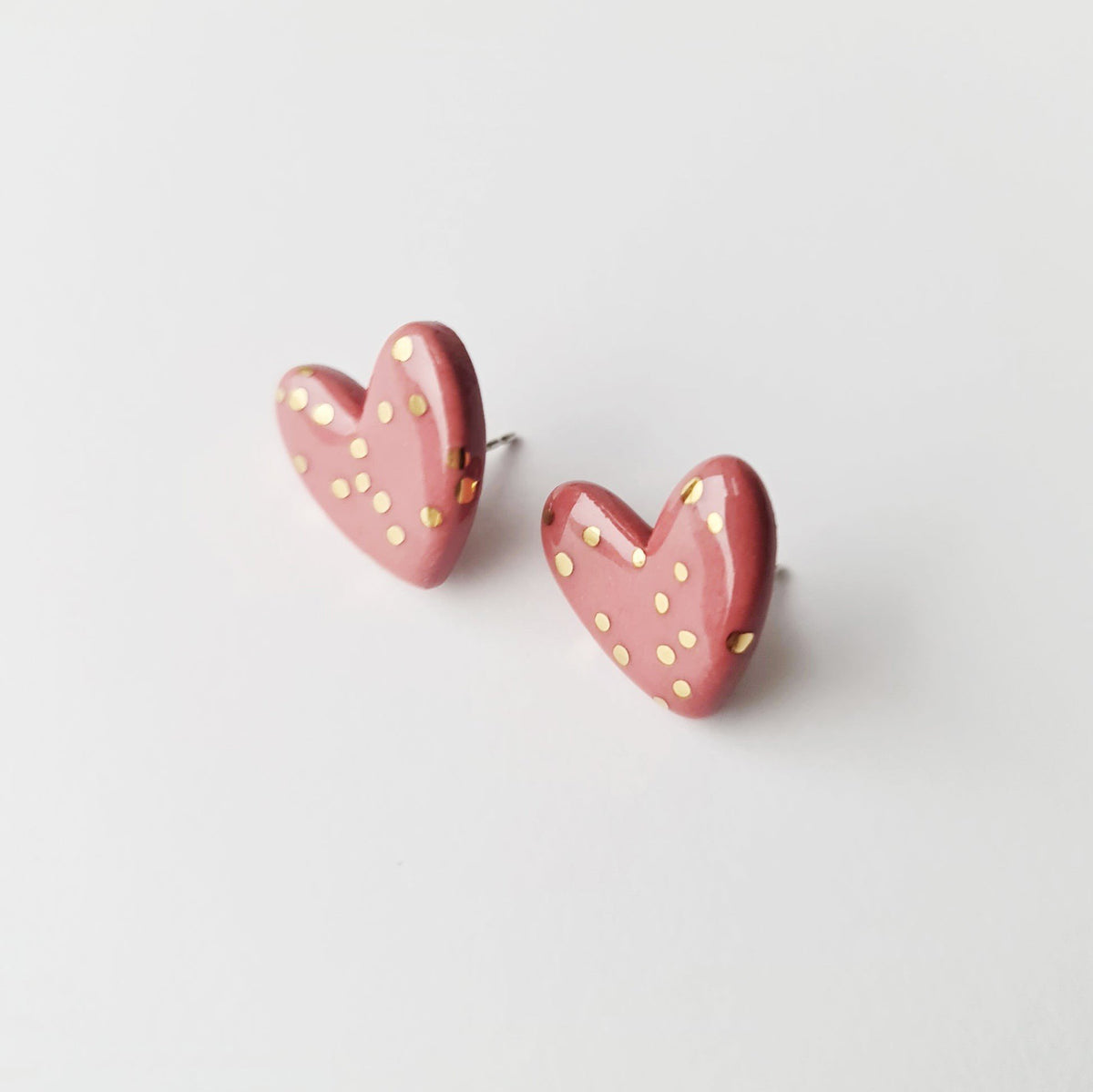 3. Studio shot of Rozenthal pink dotted porcelain heart studs with 24k gold accents on white background