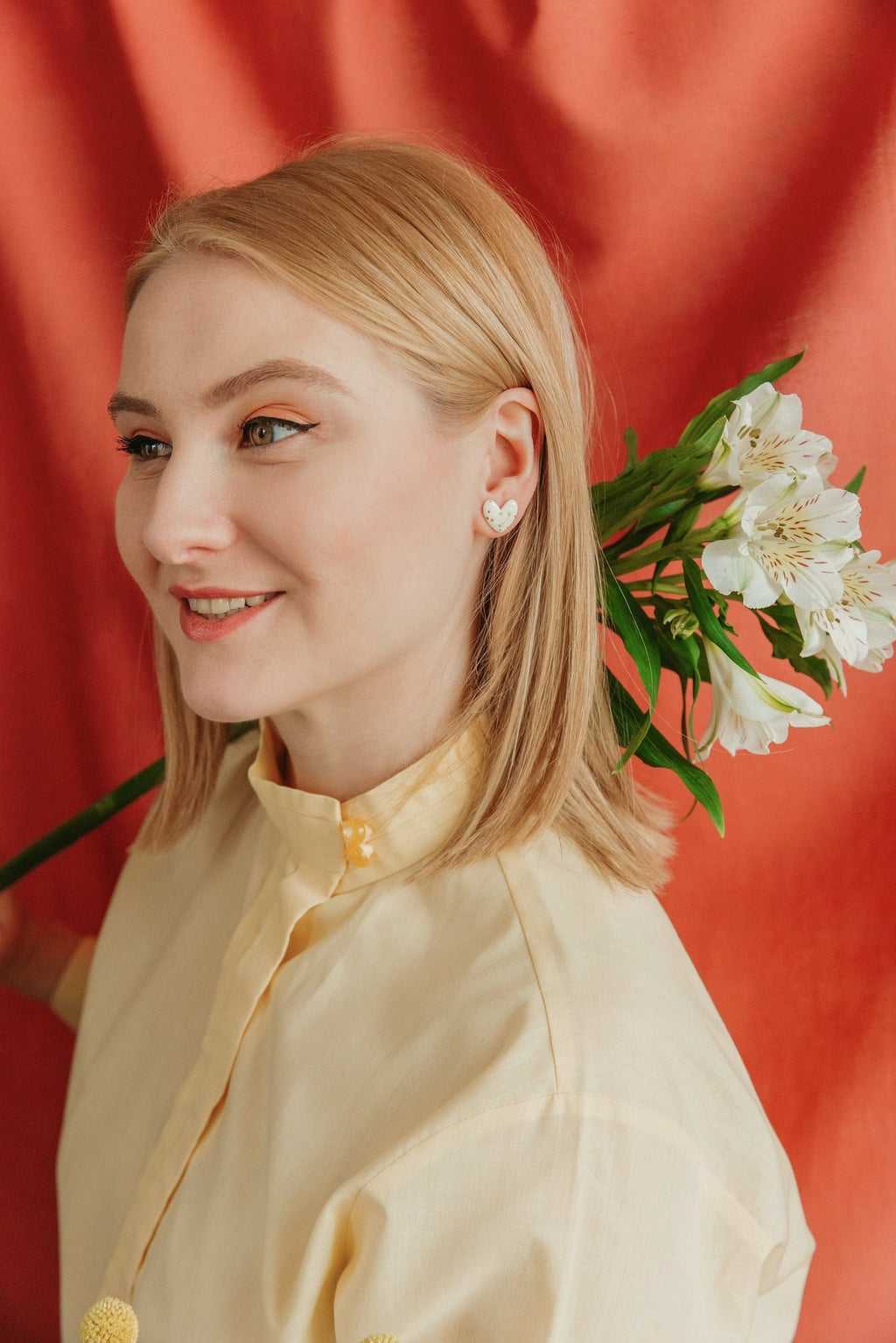 1. Woman wearing Rozenthal dotted porcelain heart studs with 24k gold accents, shown in lifestyle setting