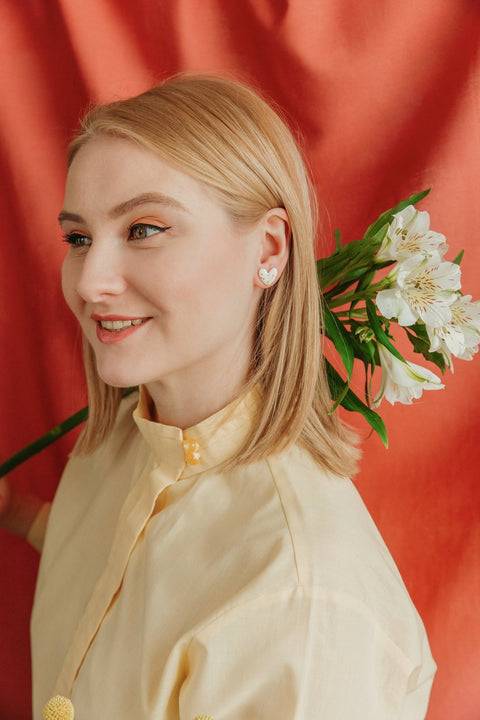 1. Woman wearing Rozenthal dotted porcelain heart studs with 24k gold accents, shown in lifestyle setting