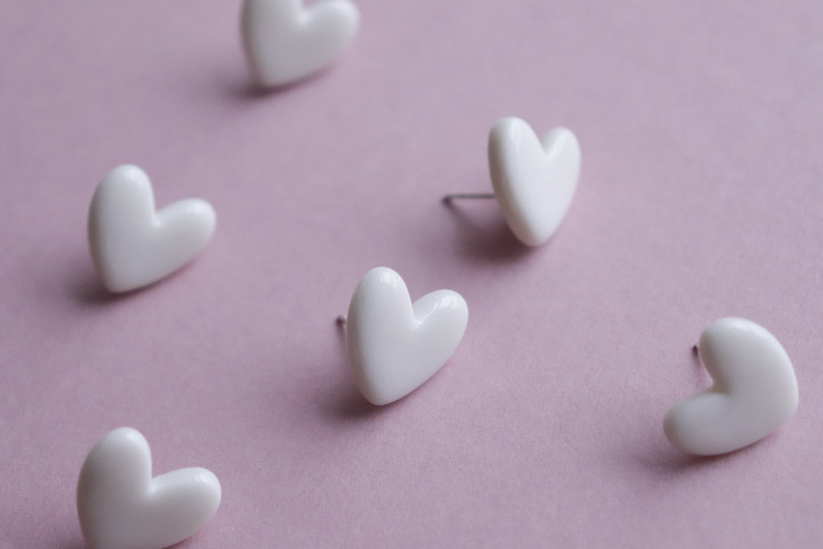 5. Flat lay of Rozenthal Porcelain Heart Studs in white on pink background, emphasizing elegant design