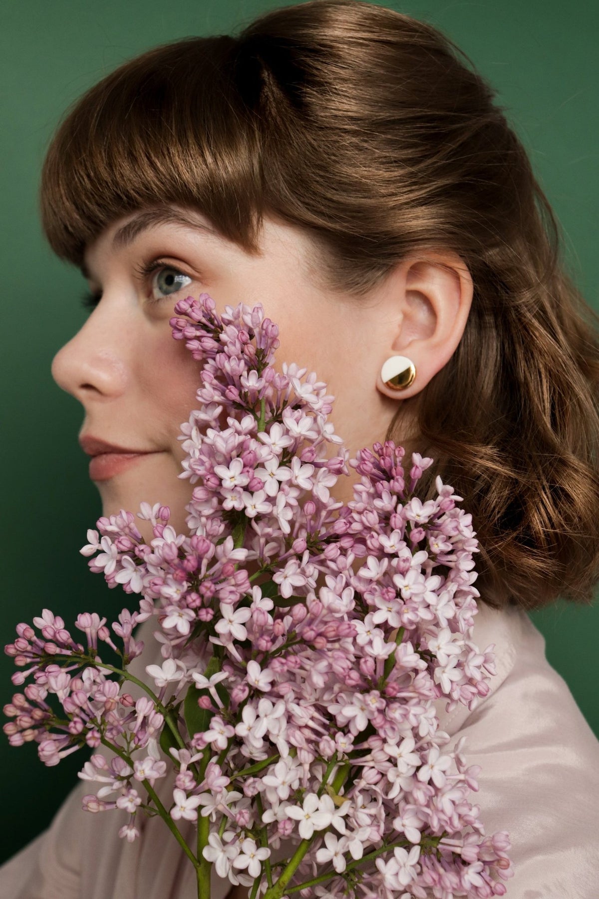 2. Side view of woman with Rozenthal black and gold porcelain stud earrings, holding flowers