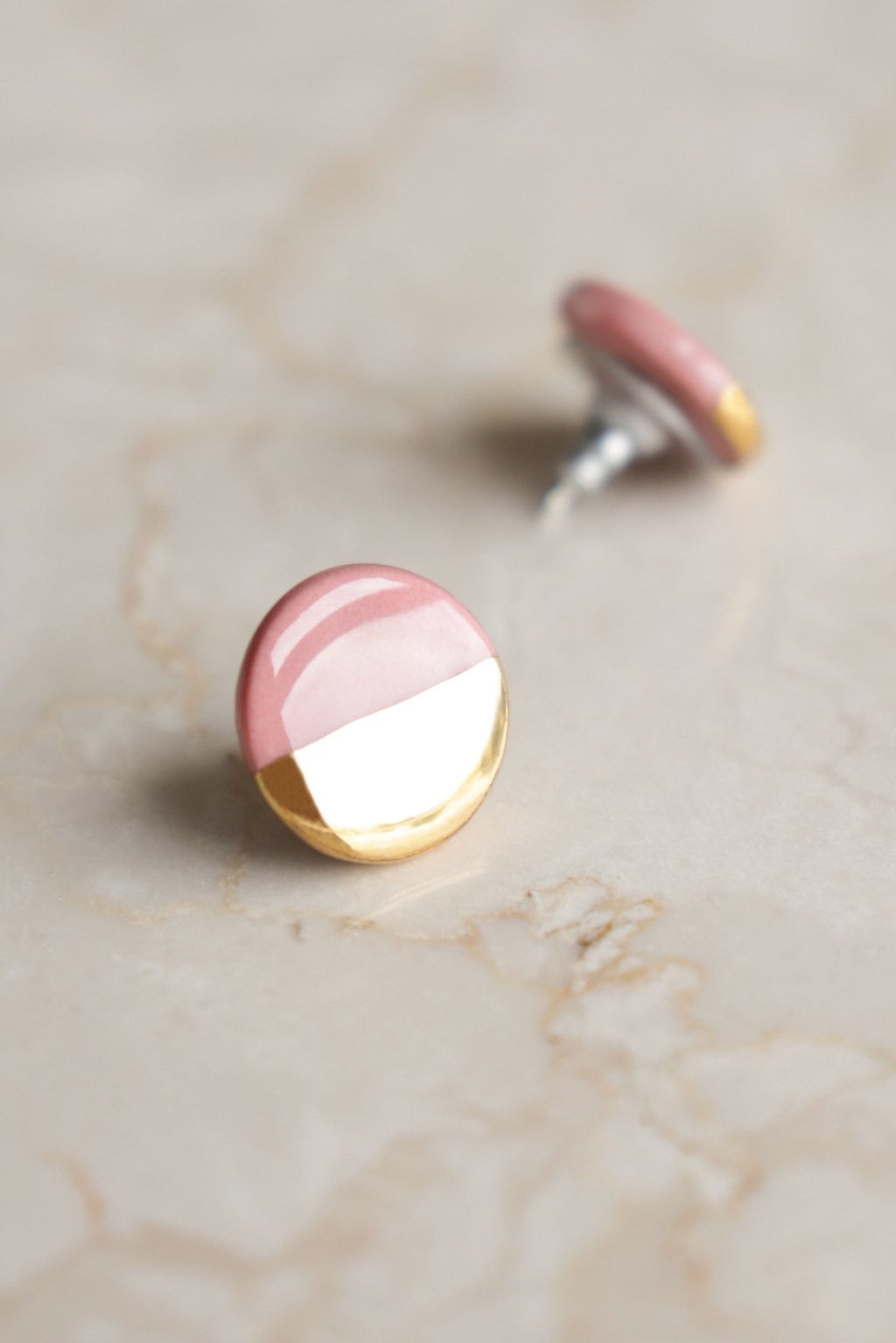 3. Close-up of Rozenthal pink and gold porcelain round stud earrings on marble surface