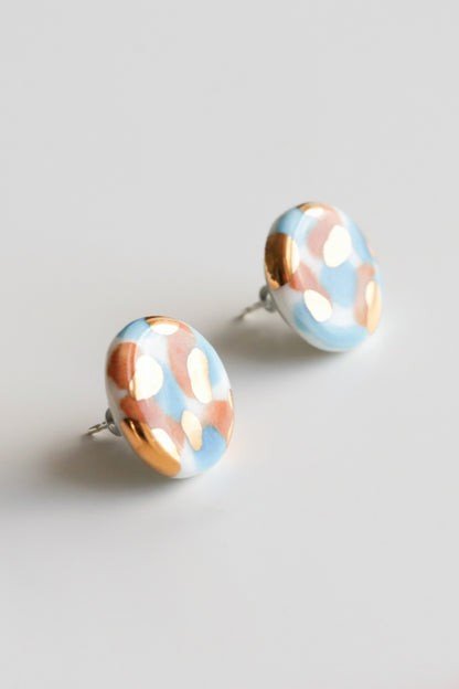 2. Close-up of Rozenthal Porcelain Tache Studs in blue and orange with 24k gold detailing, displayed in studio