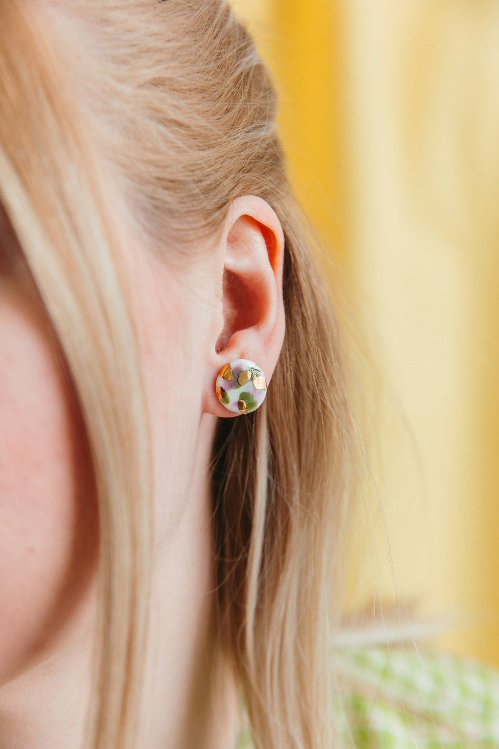 1. Woman wearing Rozenthal Porcelain Tache Studs in green and violet, showcasing hand-painted 24k gold accents