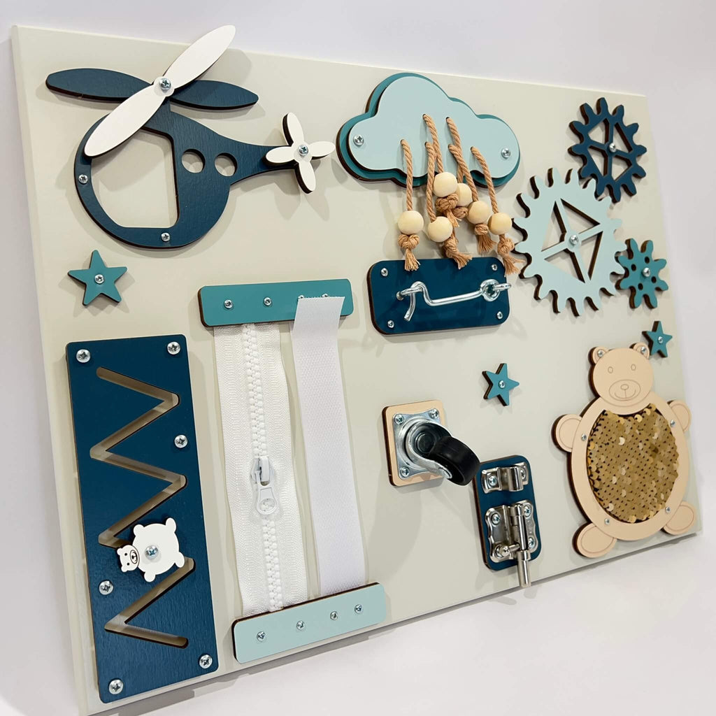3. Close-up of baby sensory busy board showing blue and beige elements like a zipper, gears, and a bear