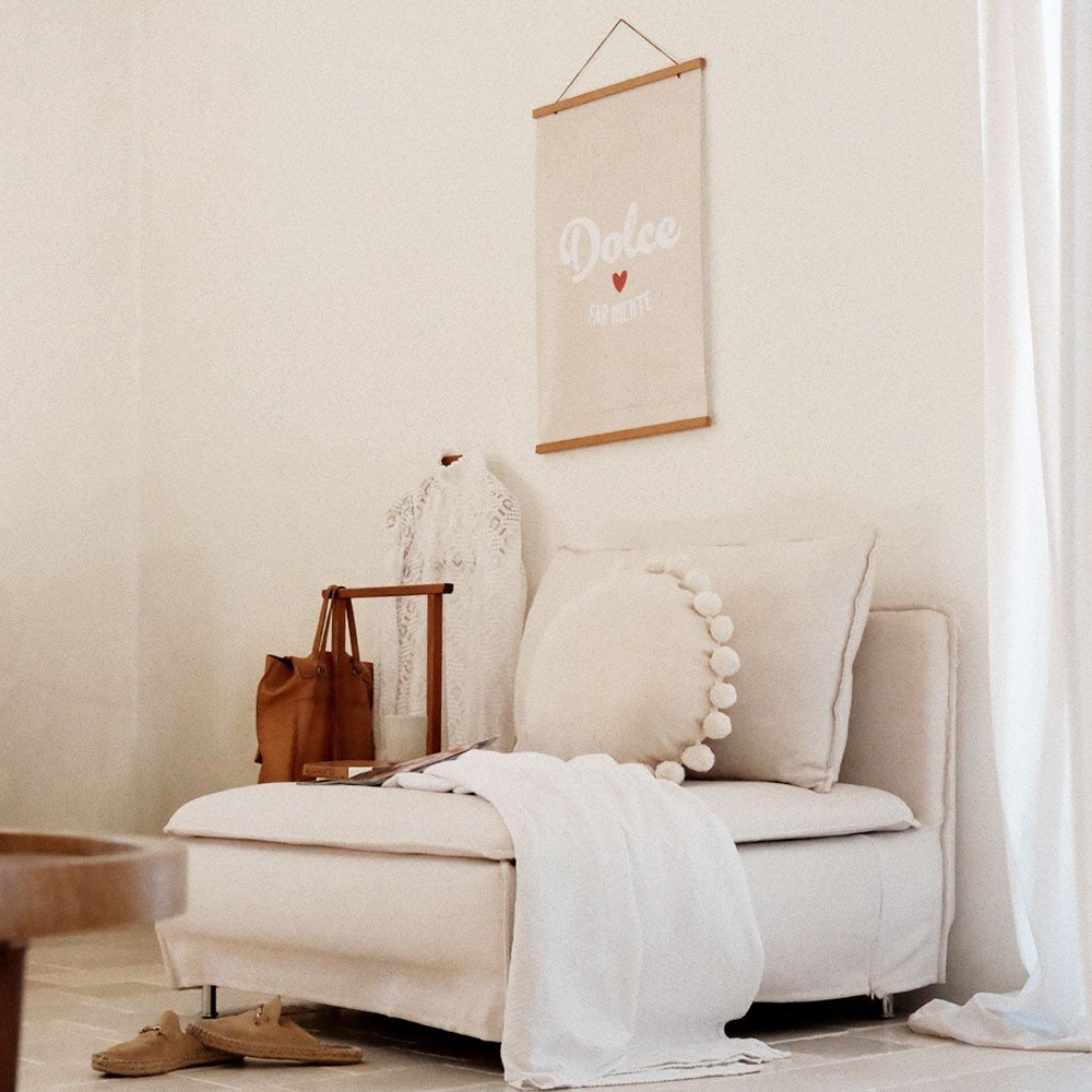 2. Beige 'Dolce far Niente' poster hanging in a cozy living room with a cream sofa, white throw, and decorative pillow