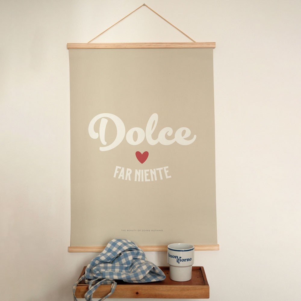 1. Minimalist poster with 'Dolce far Niente' text in white and red heart on beige background, hanging above a wooden shelf with a blue checkered cloth and a mug