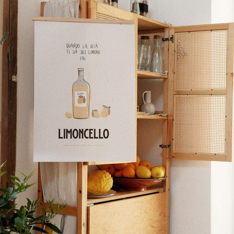 3. Terra Mamma Limoncello poster displayed on wooden cabinet with lemons and oranges in kitchen