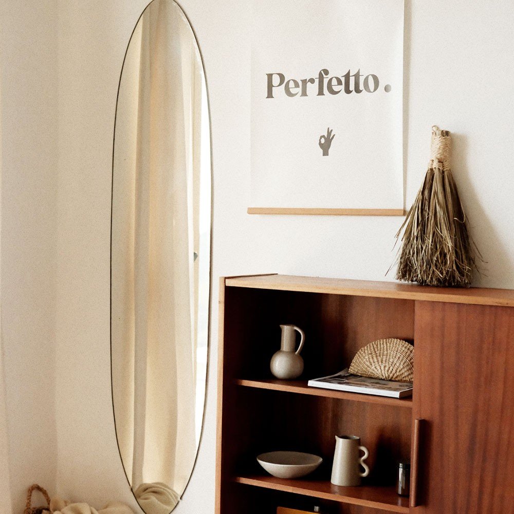 3. Perfetto poster in a modern room with a wooden cabinet, oval mirror, and decorative items