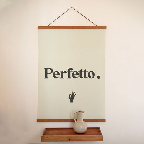 1. Perfetto poster with minimalist typography hanging on a wall above a wooden shelf with a ceramic jug