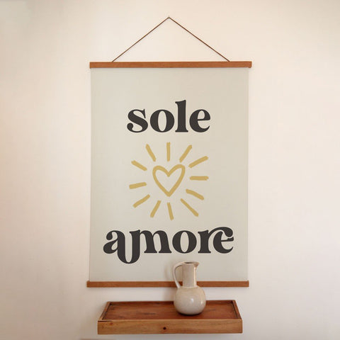 2. Sole Amore poster with Italian typography and heart design hanging on a white wall above a wooden shelf with a ceramic vase, minimalist style, Terra Mamma brand