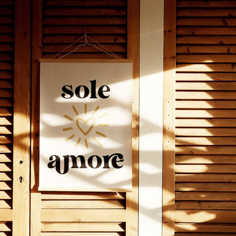 1. Sole Amore poster with Italian typography and heart design hanging on wooden shutters, casting shadows, minimalist style, Terra Mamma brand