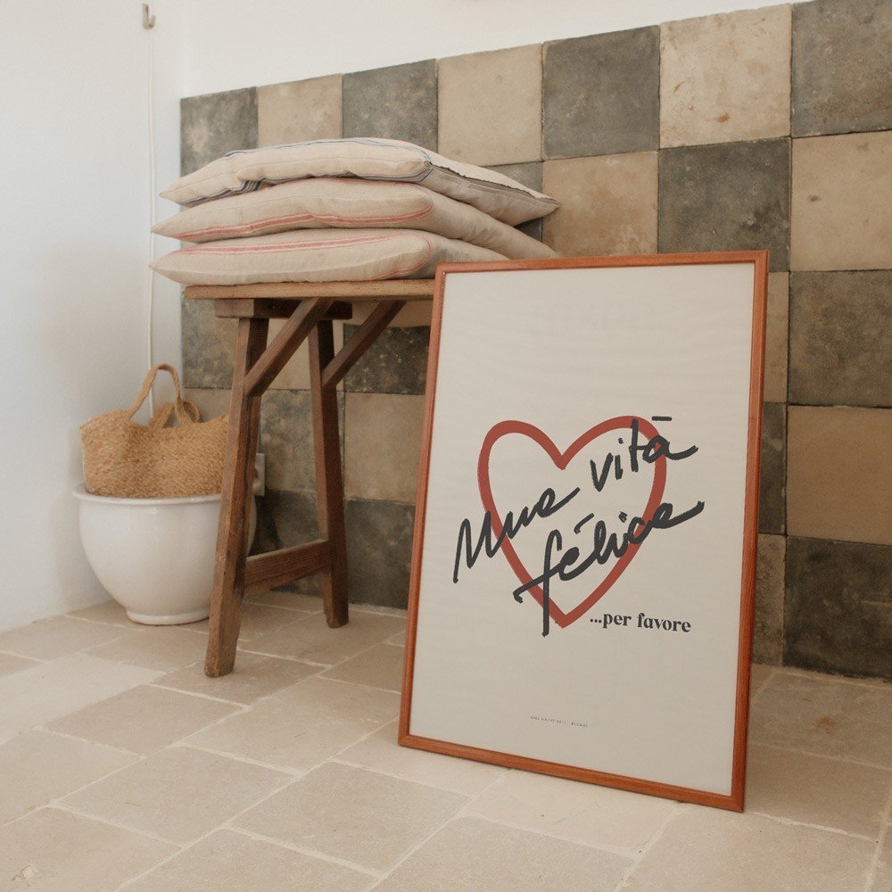 4. Framed Terra Mamma Vita Felice poster leaning against a tiled wall, next to a wooden table with cushions