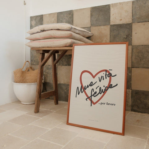 4. Framed Terra Mamma Vita Felice poster leaning against a tiled wall, next to a wooden table with cushions