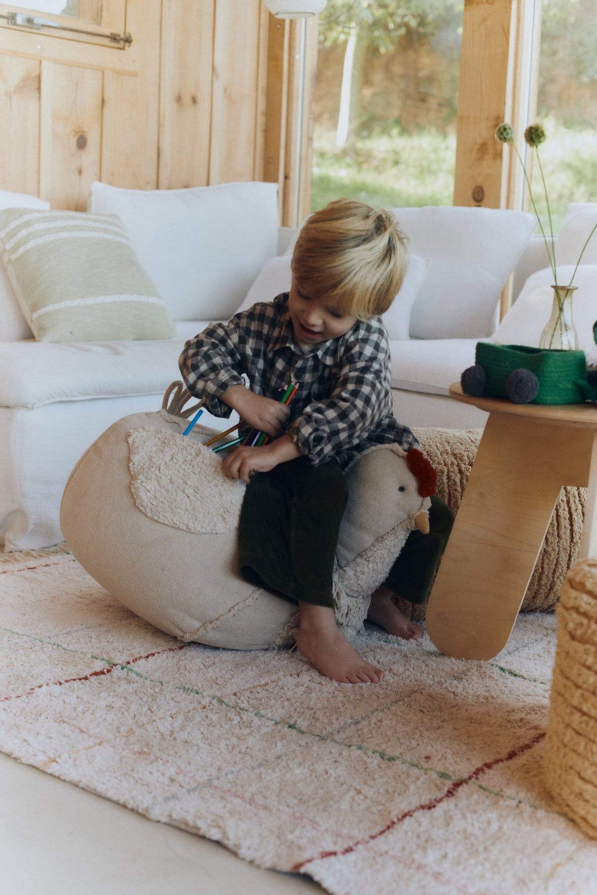 1. Child playing on beige chicken pouf in rustic living room setting