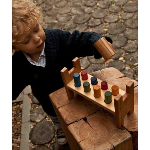 1. Child playing with Wooden Story pounding bench on wooden surface outdoors