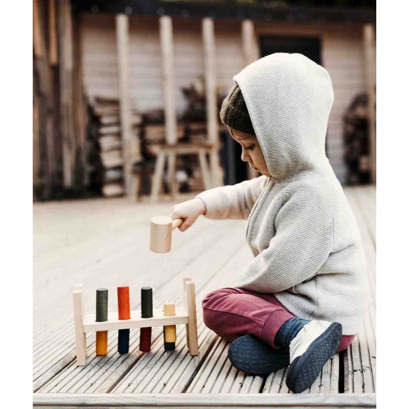 1. Child in hoodie using Wooden Story pounding bench on wooden deck