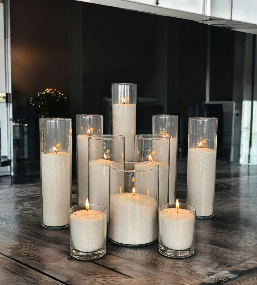 1. Multiple lit candles in glass holders arranged on wooden table in dimly lit room