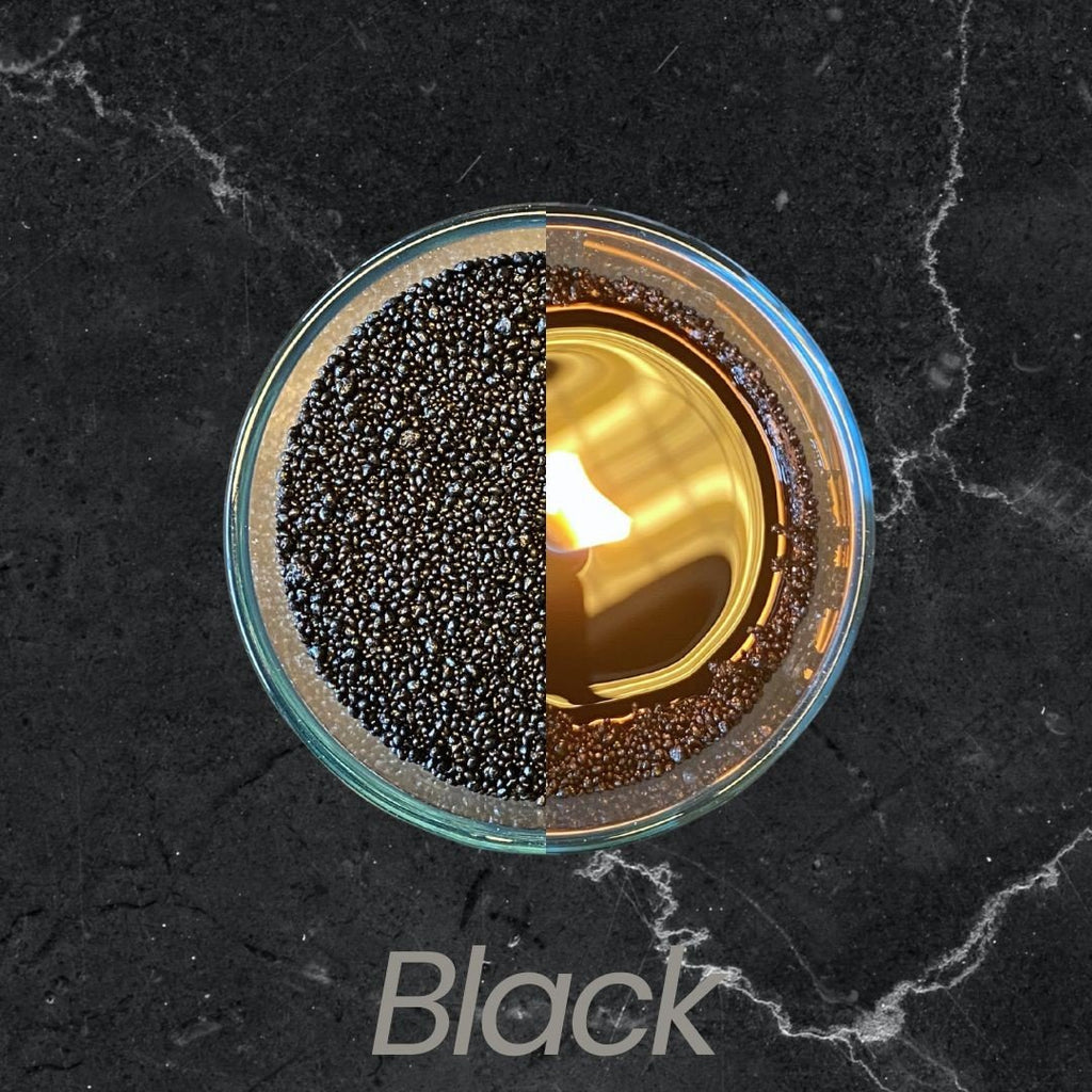 3. Top view of black powdered candle half lit, half unlit in glass container on dark marble surface