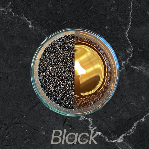 3. Top view of black powdered candle half lit, half unlit in glass container on dark marble surface