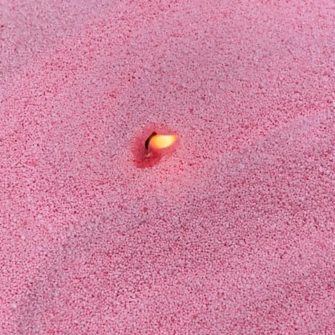 3. Close-up of lit wick in dark baby pink powdered candle wax by Candledust