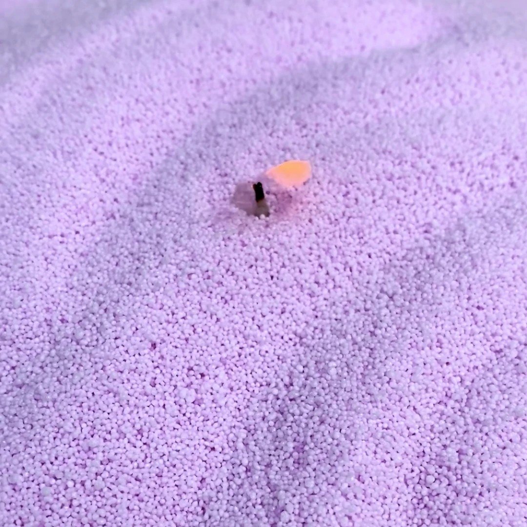 3. Close-up of light lilac candle sand with a wick inserted, showcasing fine-grained texture