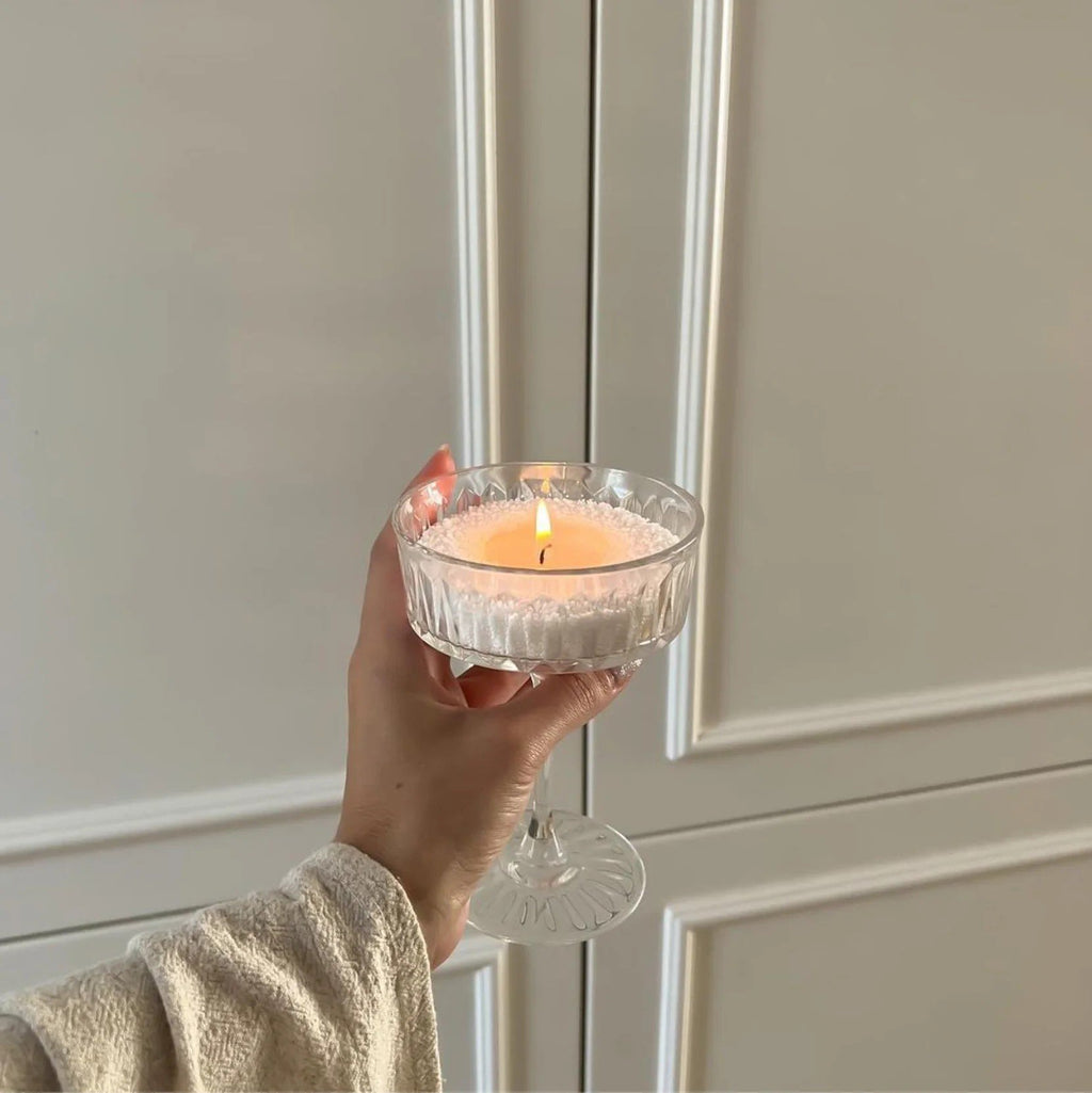 1. Woman holding a lit candle in a glass container, showcasing the powdered candle refill kit in a cozy indoor setting