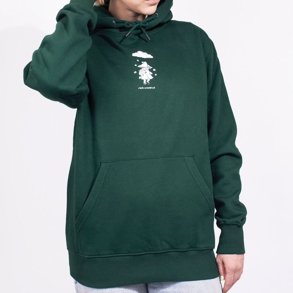1. Female model wearing green unisex hoodie with Moomin character print, hand on head, in studio setting