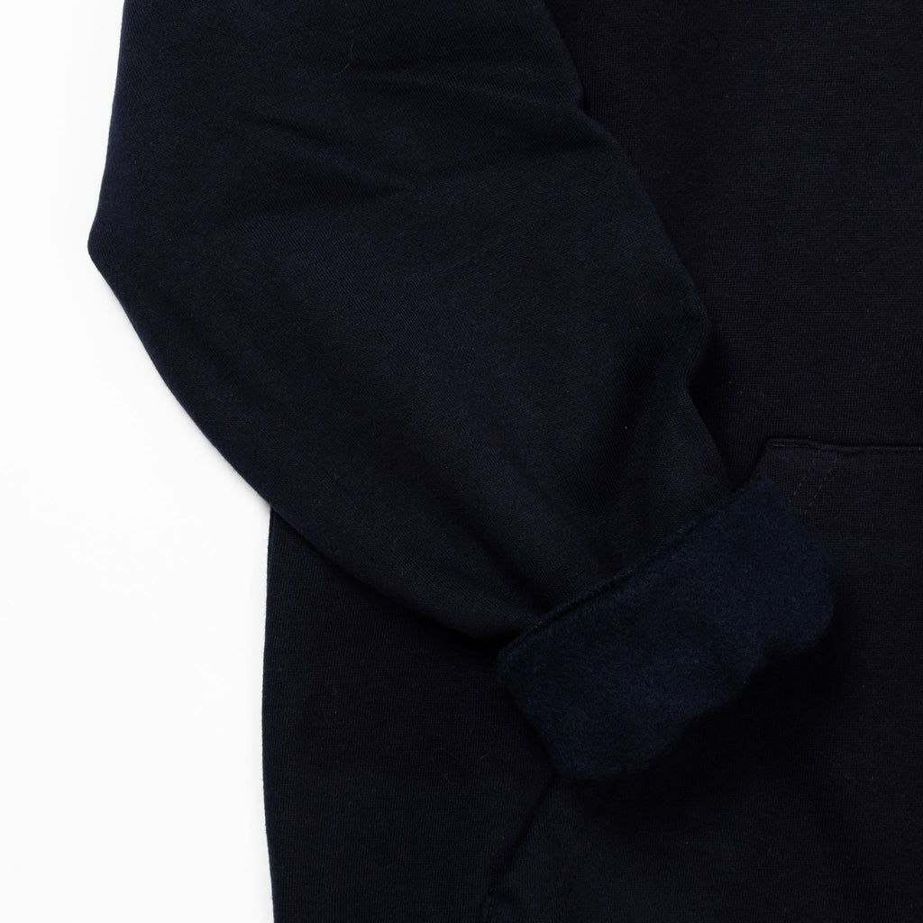 3. Close-up of navy hoodie sleeve and pocket detail highlighting fabric texture