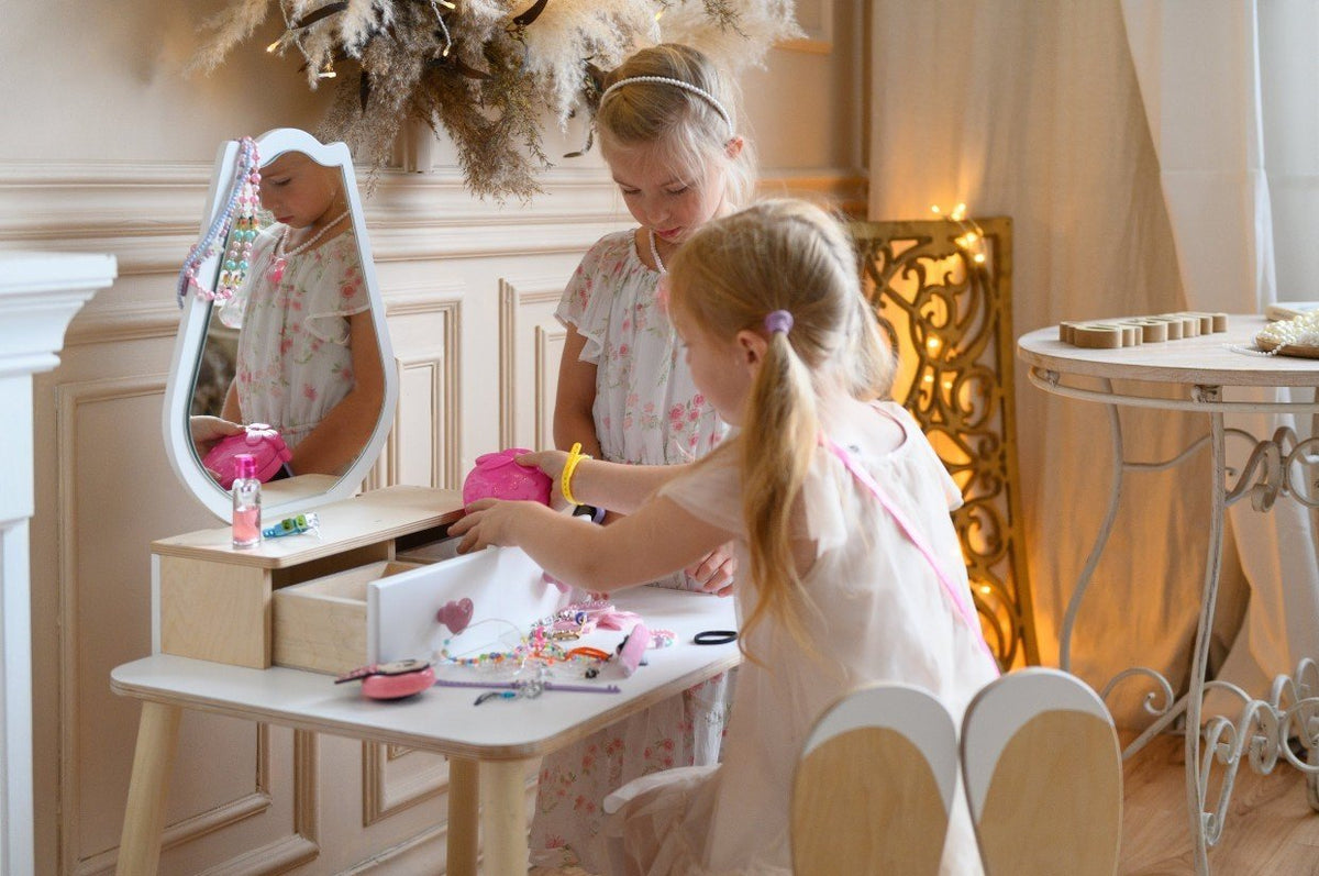 1. Two girls engaging in imaginative play with a white beauty table set in a stylish room.