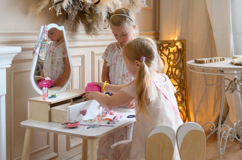 1. Two girls engaging in imaginative play with a white beauty table set in a stylish room.