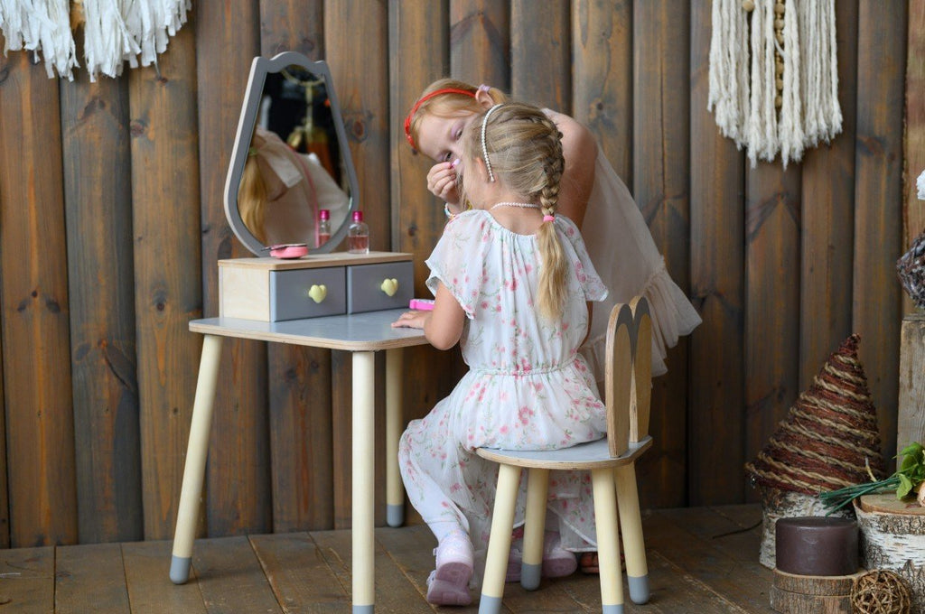 1. Two girls playing with a grey beauty table set in a rustic room, fostering creativity.