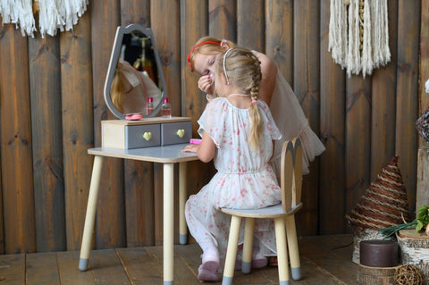1. Two girls playing with a grey beauty table set in a rustic room, fostering creativity.